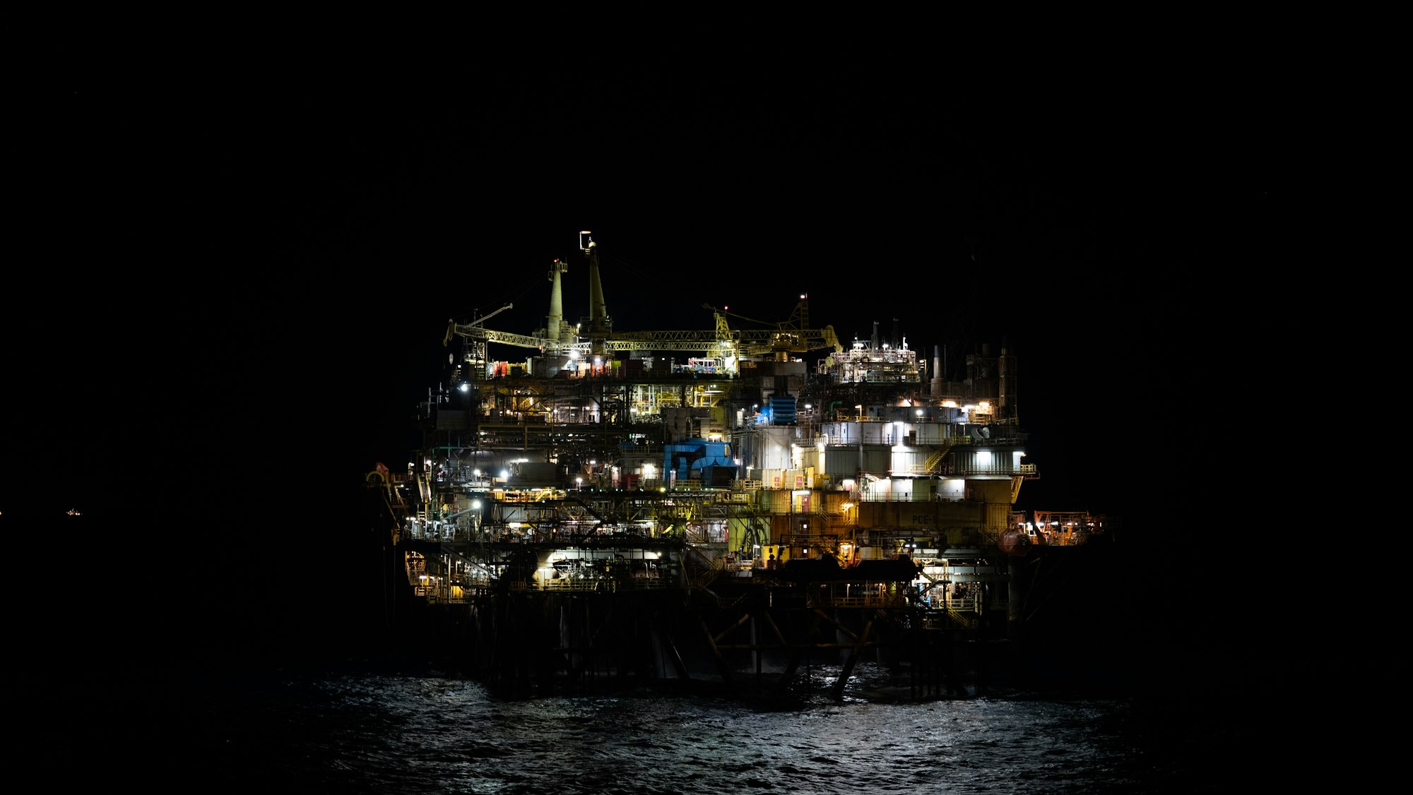 Offshore oil platform lit at night, standing in dark water
